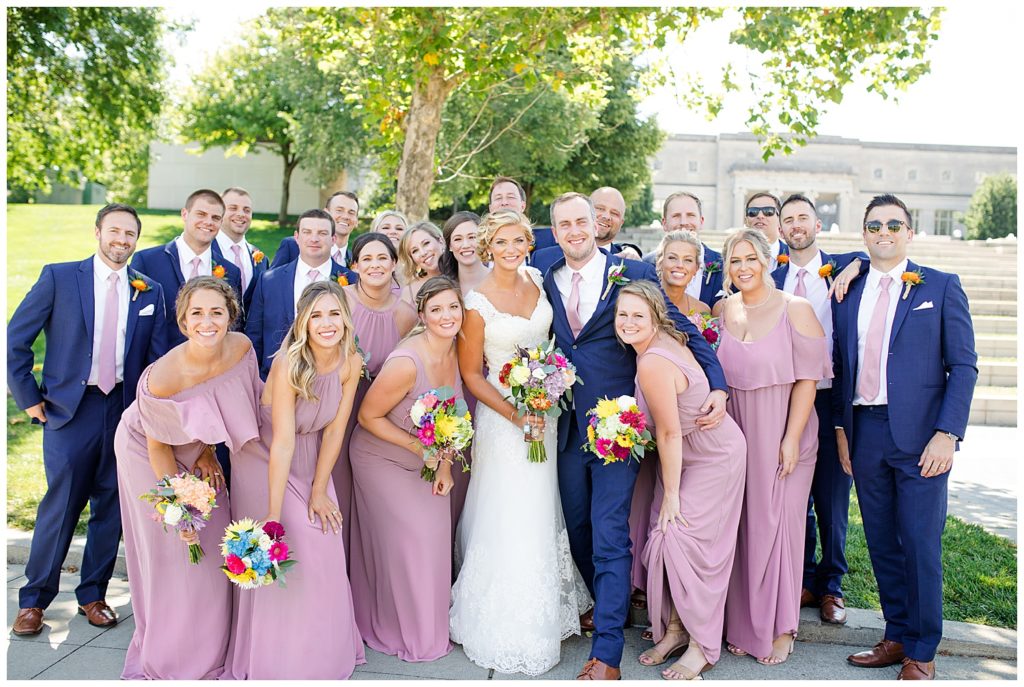 bridal party huddled around bride and groom in front of steps at cosi