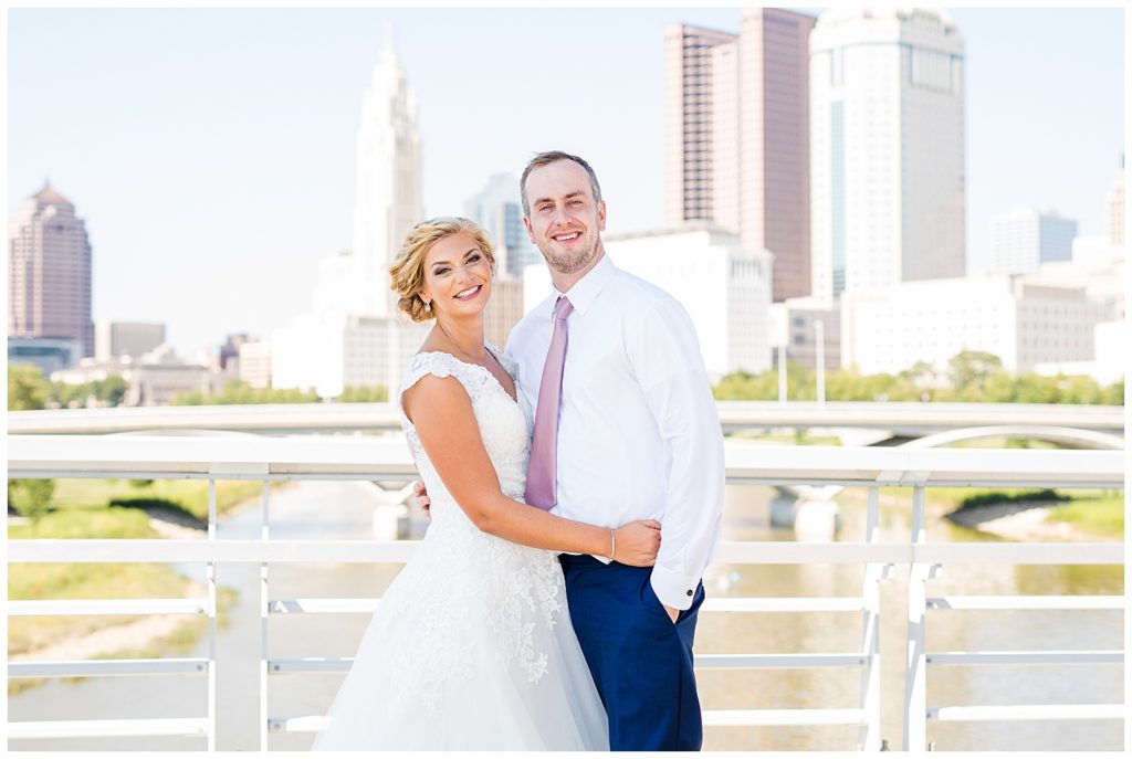bride and groom smiling at camera with columbus skyline in background