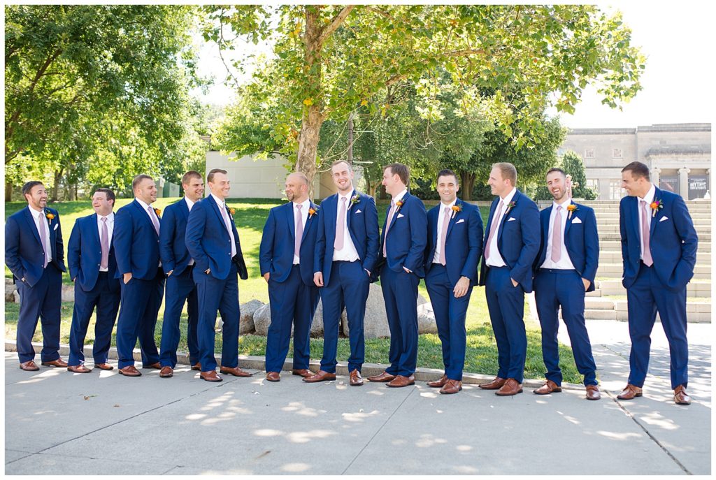 groom and groomsmen laughing in front of steps at cosi