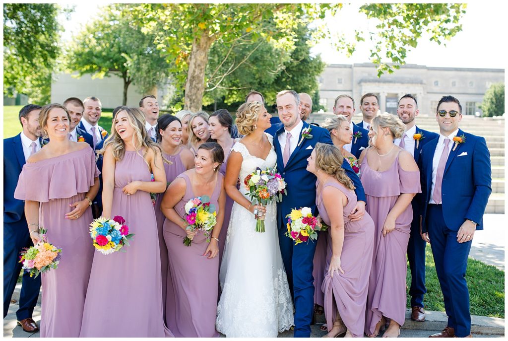 bridal party gathered around each other and laughing in front of steps at cosi