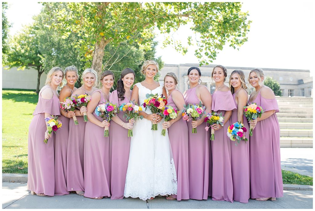 bride and bridesmaids smiling at camera in front of steps at cosi