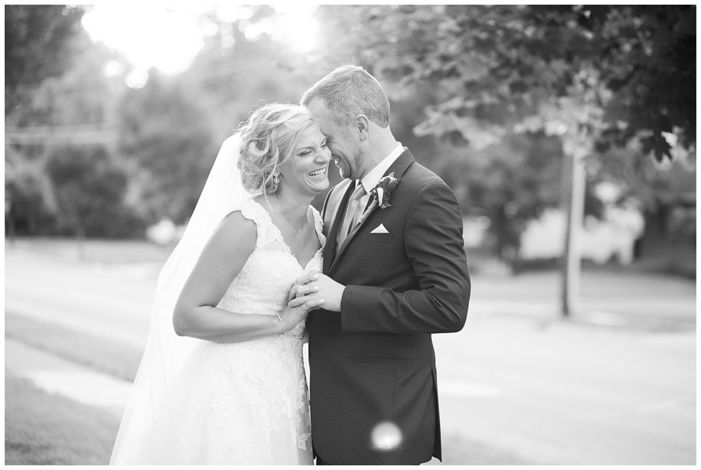 black and white image of bride laughing while groom nuzzles into her