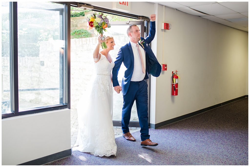 bride and groom cheering as they walk into reception
