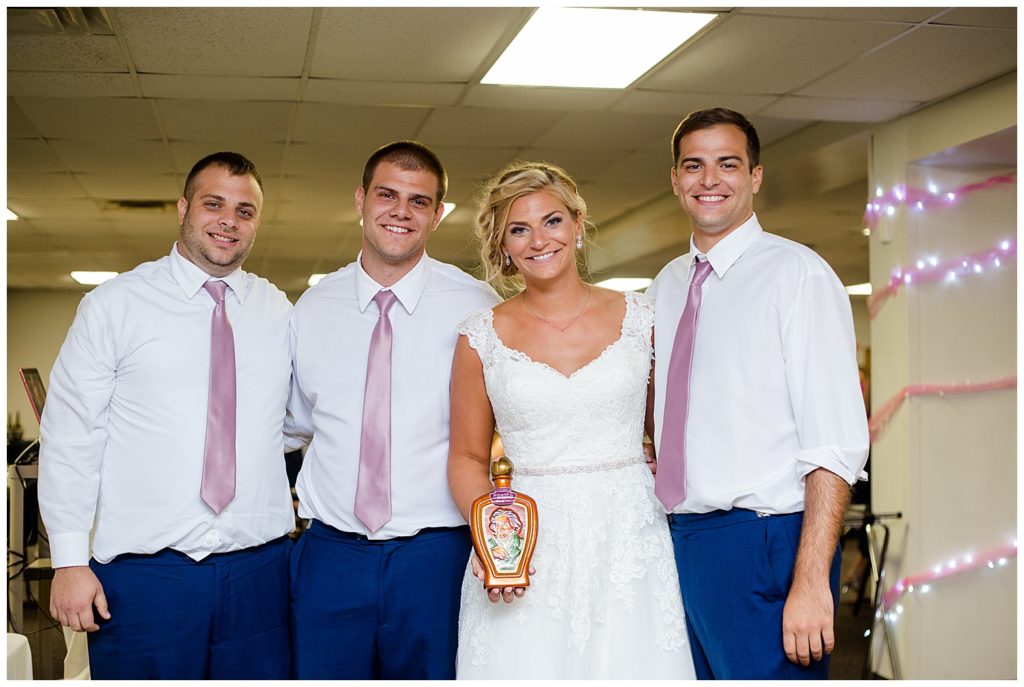 bride and brothers with vintage bottle of whiskey