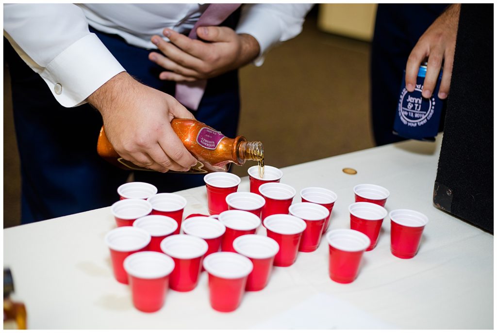 groomsman pouring shots of whiskey