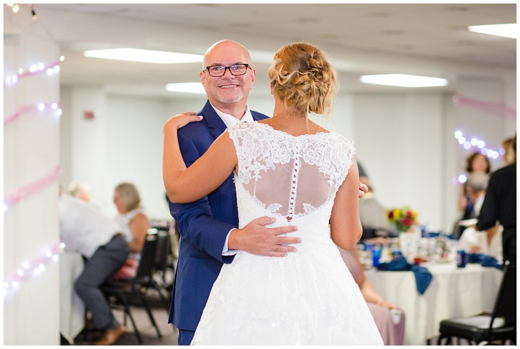 father smiling as he dances with bride