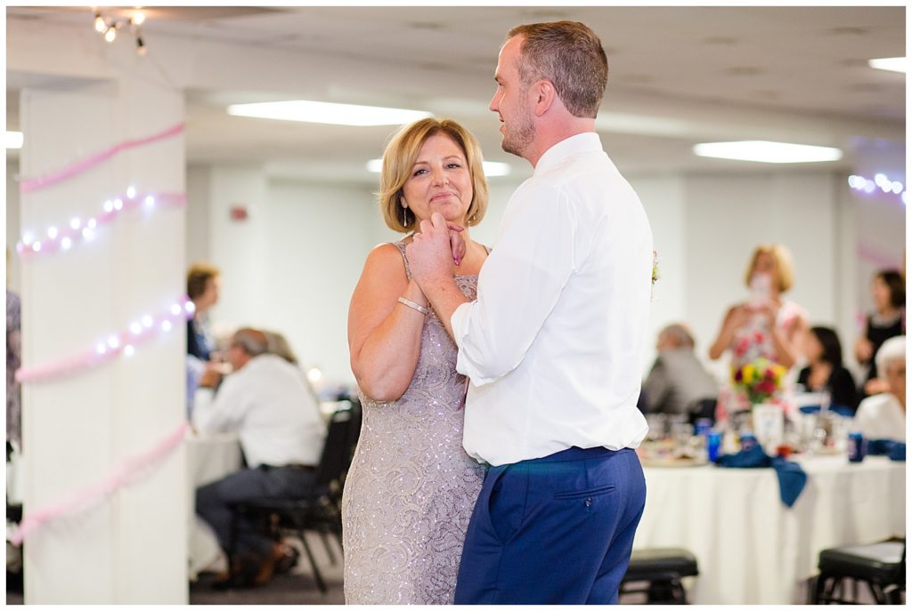 mother smiling as she dances with groom