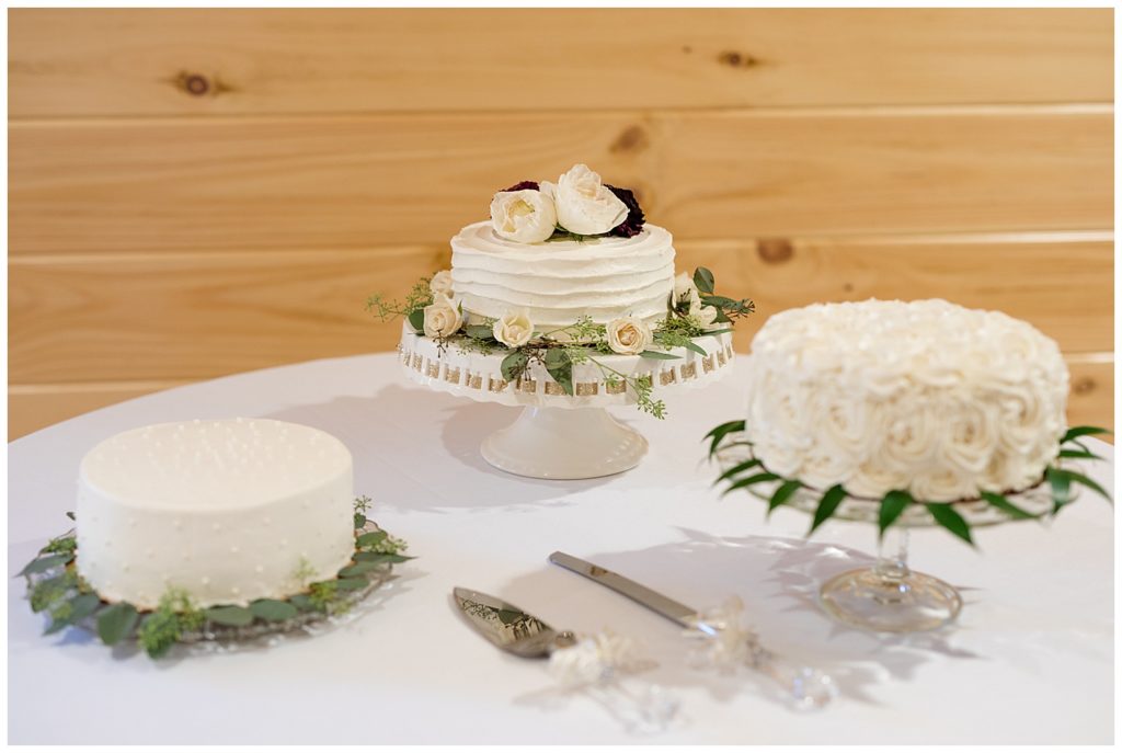 A photograph of the wedding cakes arranged on a beautiful table at the wedding reception at the Cedar Grove Lodge venue in Hocking Hills, Ohio by Columbus OH wedding photographer, Alayna Parker Photography