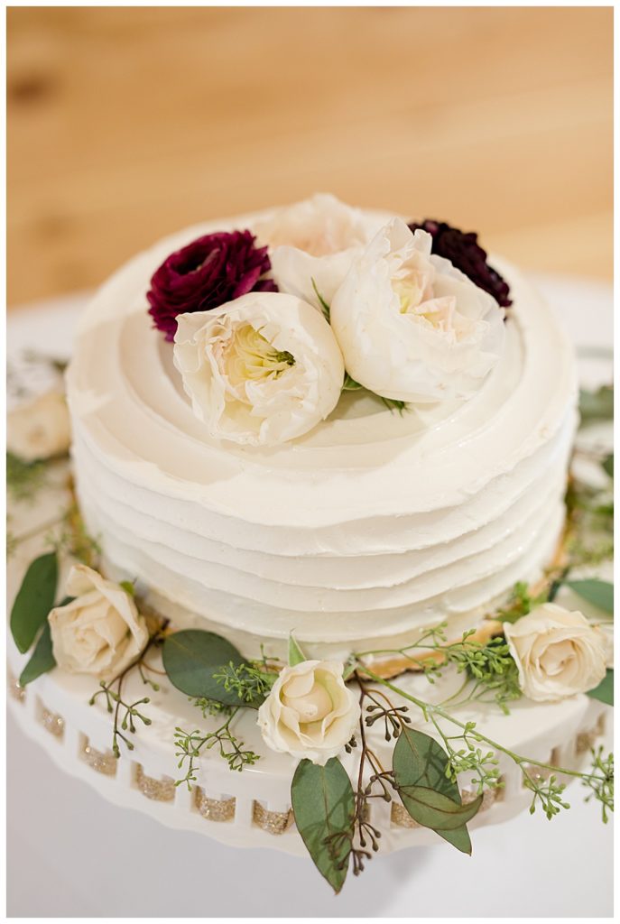A picture of a closeup look at the wedding cake decorated with pretty roses at the Cedar Grove Lodge wedding venue by Columbus wedding photographer, Alayna Parker Photography