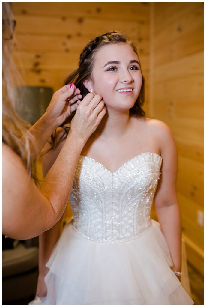 An image of the bride with her mother helping to put on her earrings as she finishes dressing for the wedding ceremony at the Cedar Grove Lodge wedding venue by Columbus Ohio wedding photographer, Alayna Parker Photography
