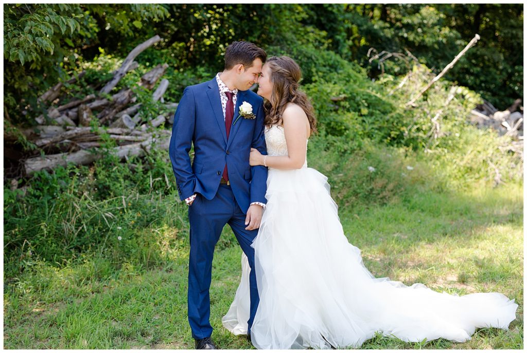 A photograph of the bride and groom tenderly touching foreheads as they stand close together in a beautiful outdoor setting at the Cedar Grove Lodge wedding venue by Columbus OH wedding photographer, Alayna Parker Photography