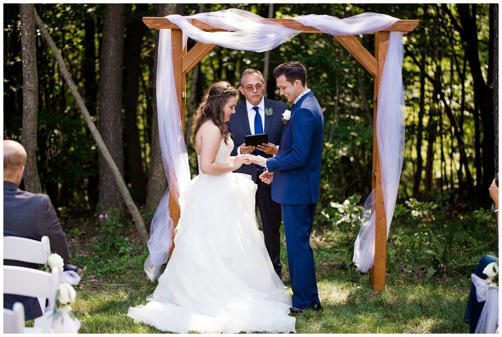 A picture of the bride and groom exchanging rings during their wedding ceremony in a beautiful outdoor setting at the Cedar Grove Lodge wedding venue by Columbus wedding photographer, Alayna Parker Photography