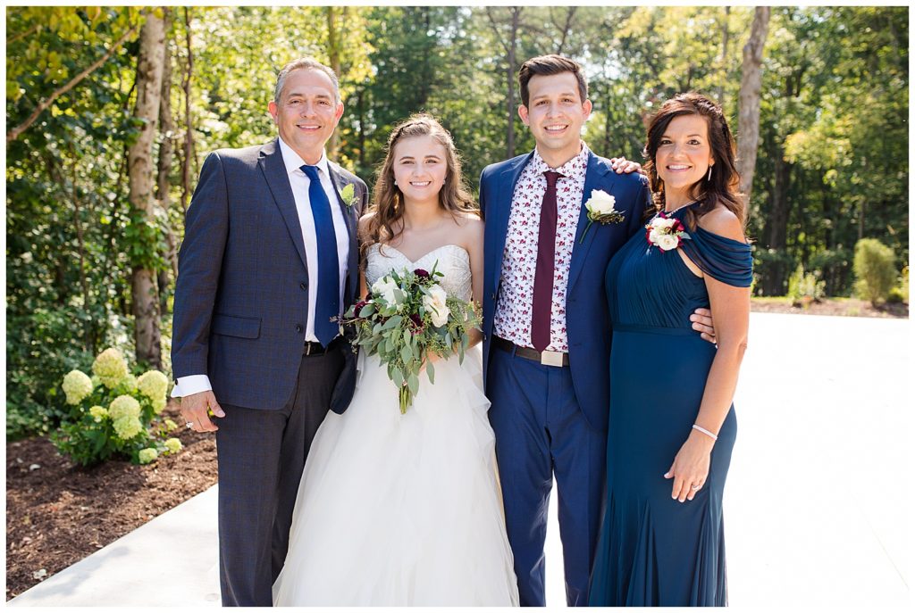 A picture of the bride and groom smiling with their parents after the wedding at the Cedar Grove Lodge venue in Hocking Hills, Ohio by Columbus wedding photographer, Alayna Parker Photography
