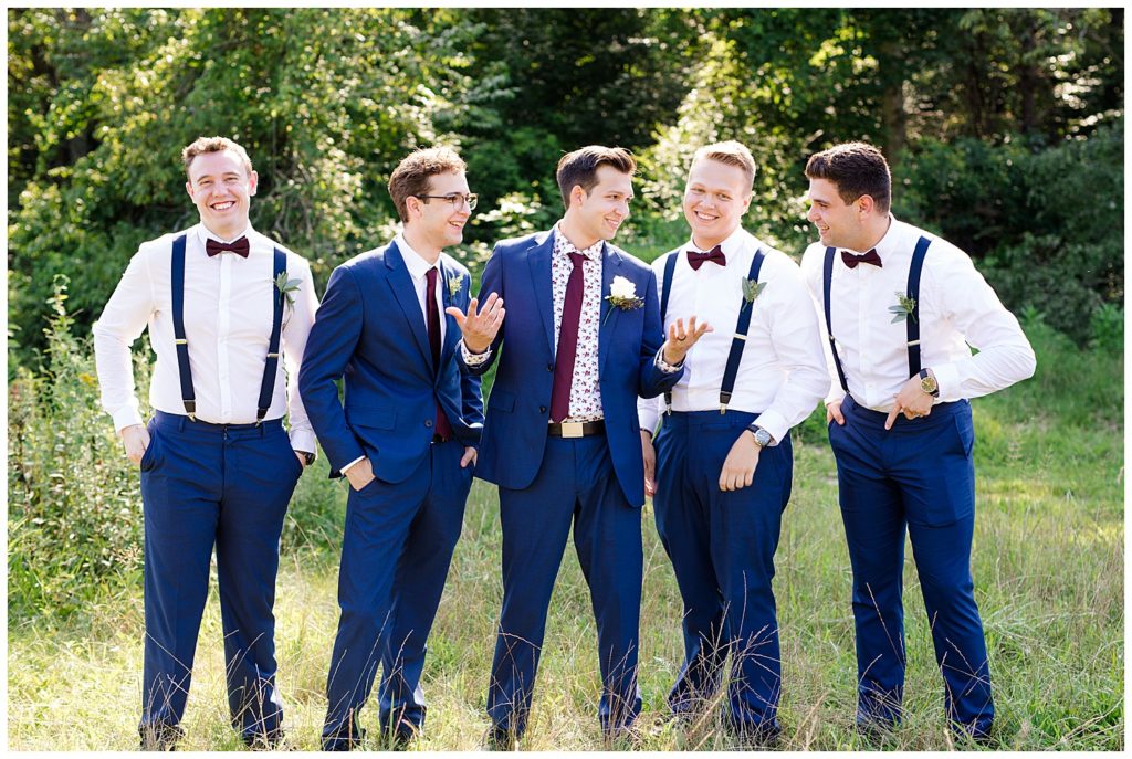 groom and groomsmen laughing and talking in field at cedar grove lodge