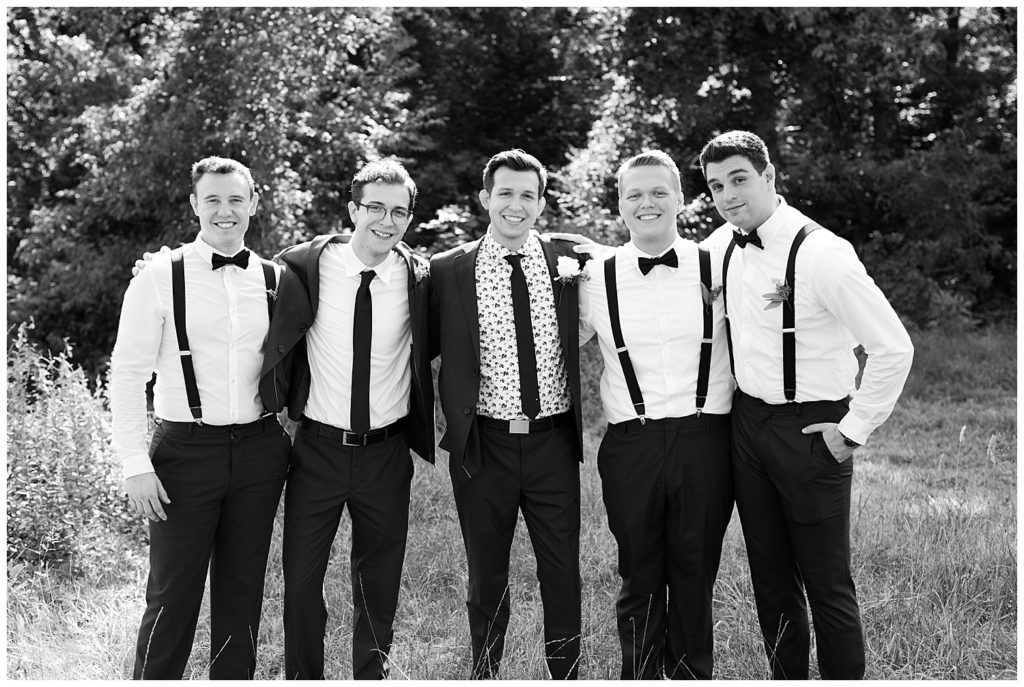 black and white image of groom and groomsmen with arms around each other
