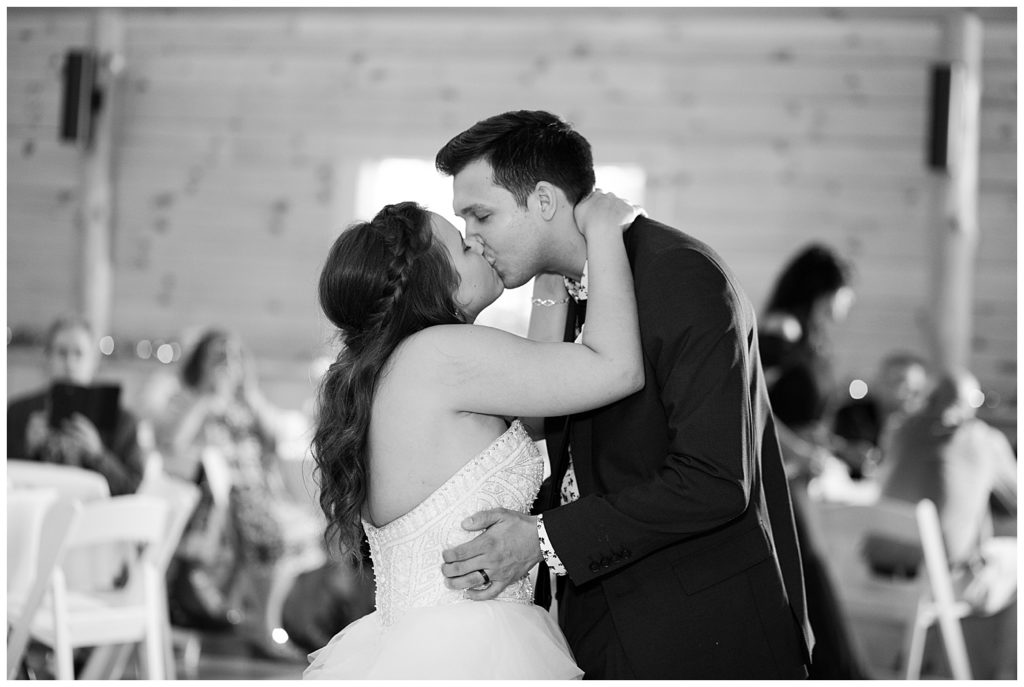 black and white image of bride and groom kissing after first dance