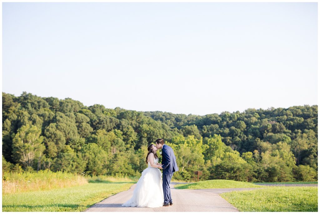 bride and groom kissing on top of hill overlooking trees at cedar grove lodge