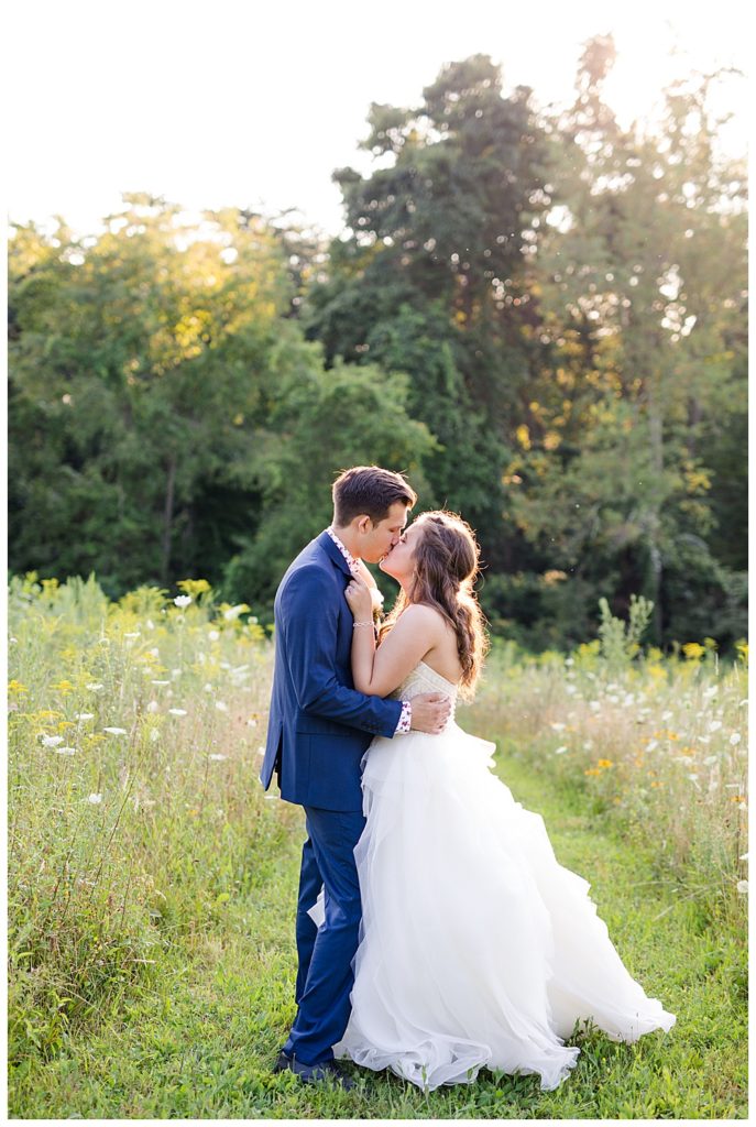 bride and groom kissing in field at golden hour at cedar grove lodge