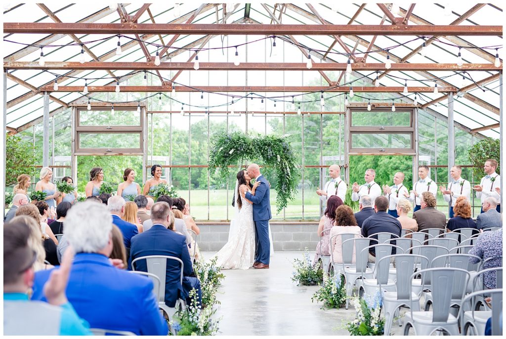 An image of a long-range view of the bride and groom kissing after their vows at their wedding ceremony at the Oak Grove venue in New Albany, Ohio by Columbus Ohio wedding photographer, Alayna Parker Photography