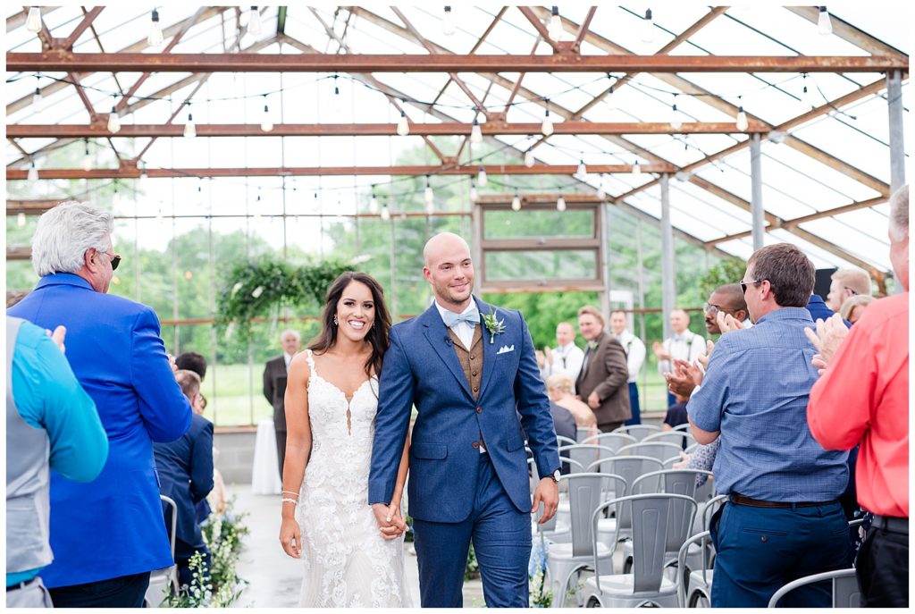 A photograph of the bride and groom walking down the aisle after their wedding ceremony, smiling as the guests clap at the Oak Grove wedding venue by Columbus OH wedding photographer, Alayna Parker Photography