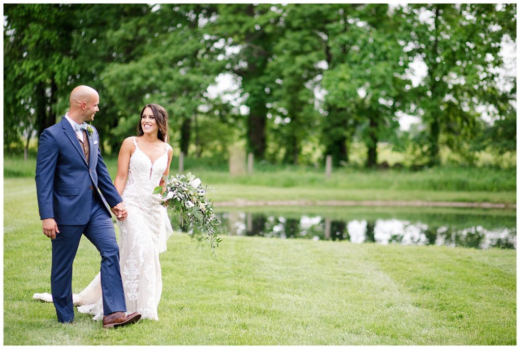 A picture of the bride and groom smiling and walking in a beautiful outdoor setting at the Oak Grove wedding venue by Columbus wedding photographer, Alayna Parker Photography