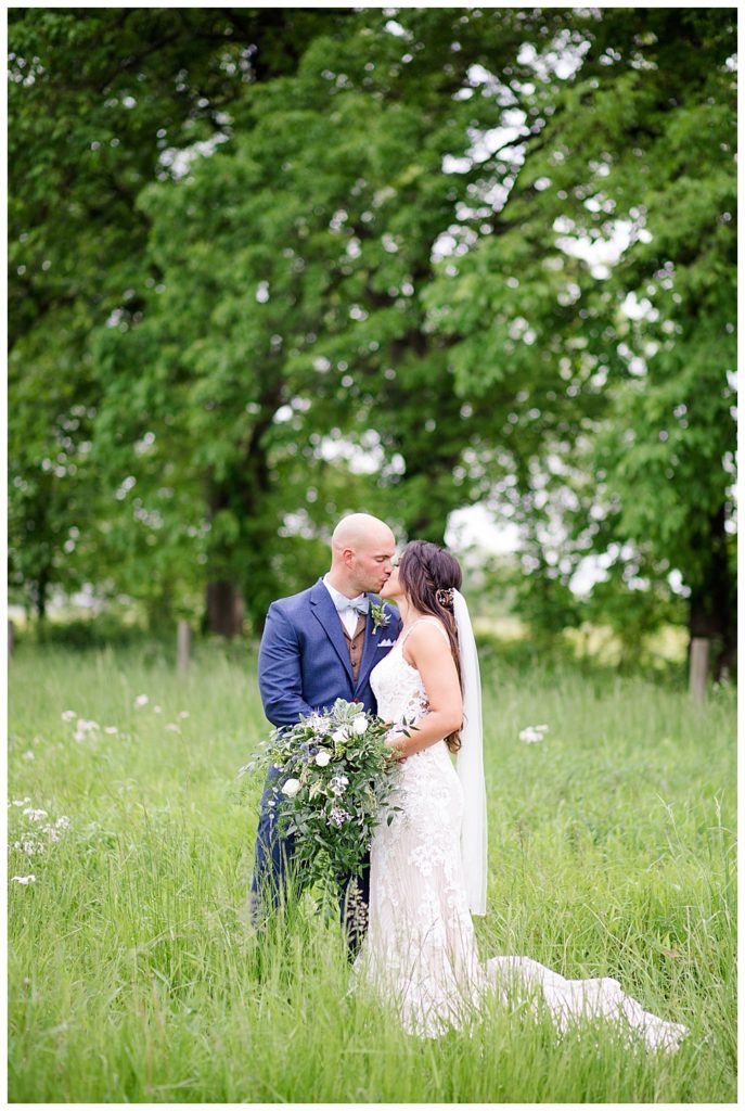 A picture of the bride and groom romantically kissing in a beautiful outdoor setting at the Oak Grove venue in New Albany, Ohio by Columbus wedding photographer, Alayna Parker Photography
