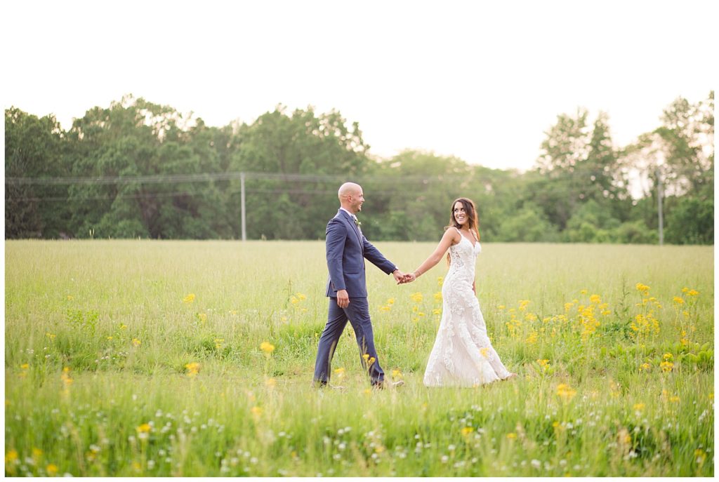 bride and groom walking through field during golden hour at jorgensen farms oak grove