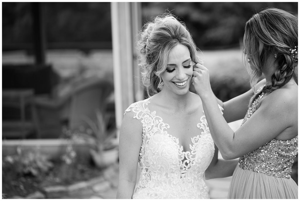 black and white image of sister putting bride's earring in