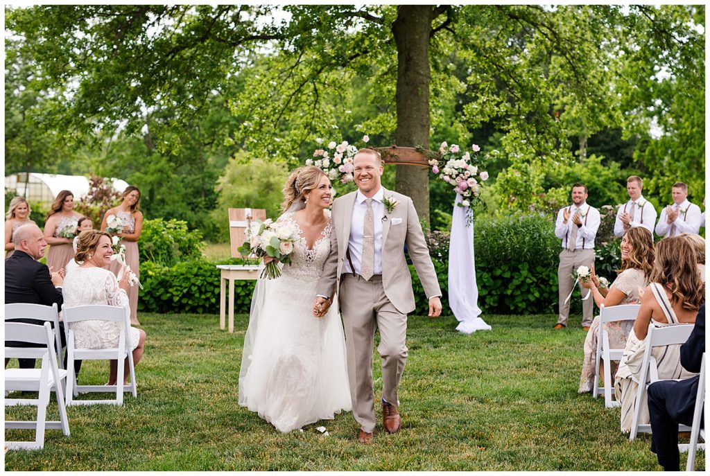 bride and groom laughing as they walk up aisle after wedding ceremony at jorgensen farms