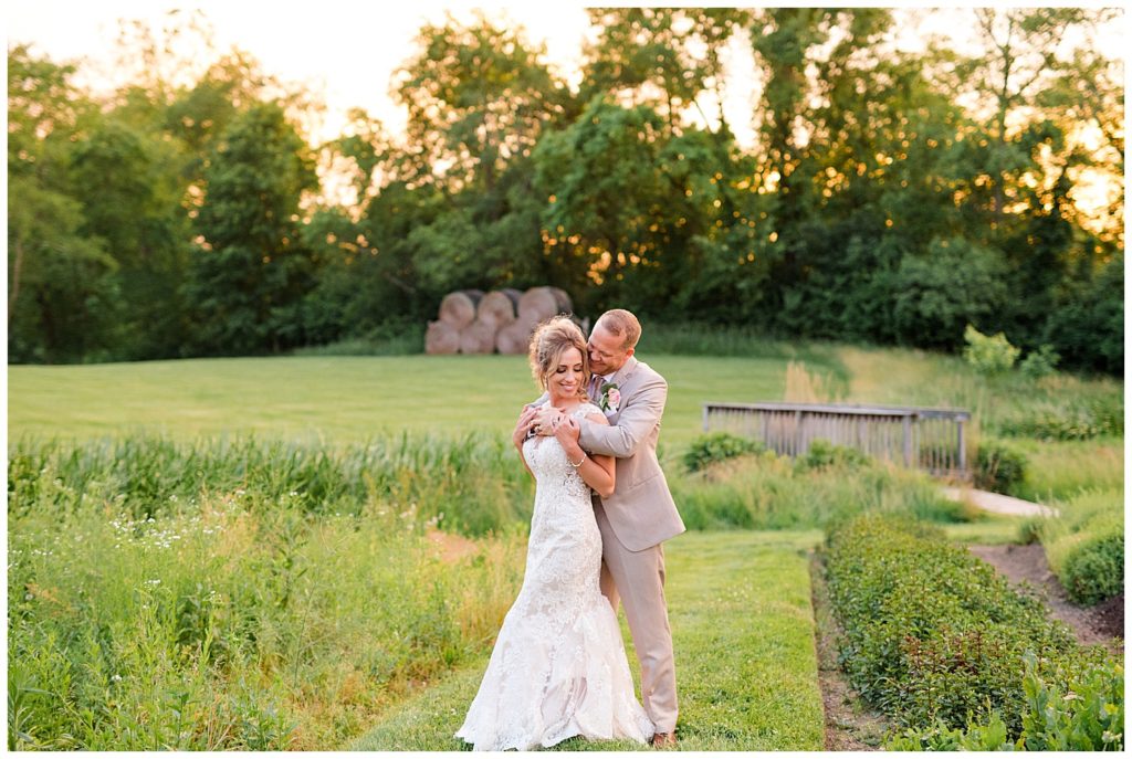 bride and groom hugging in field at sunset at jorgensen farms