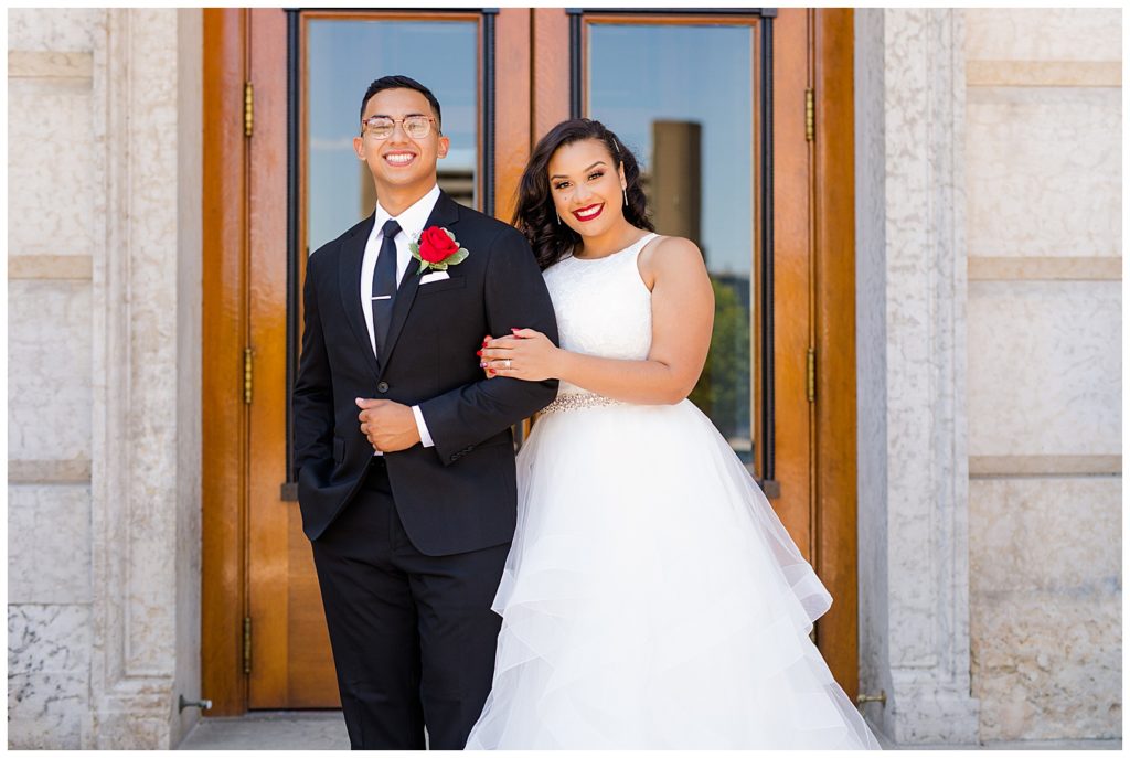 bride holding on groom's arm in front of ohio statehouse