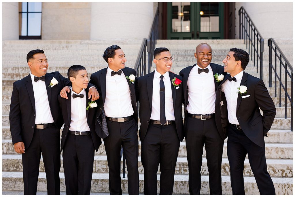 groom and groomsmen laughing with arms around each other at ohio statehouse