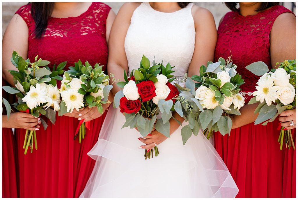 bridesmaids hold bouquets of white and green flowers and bride holds bouquet of with red and white roses