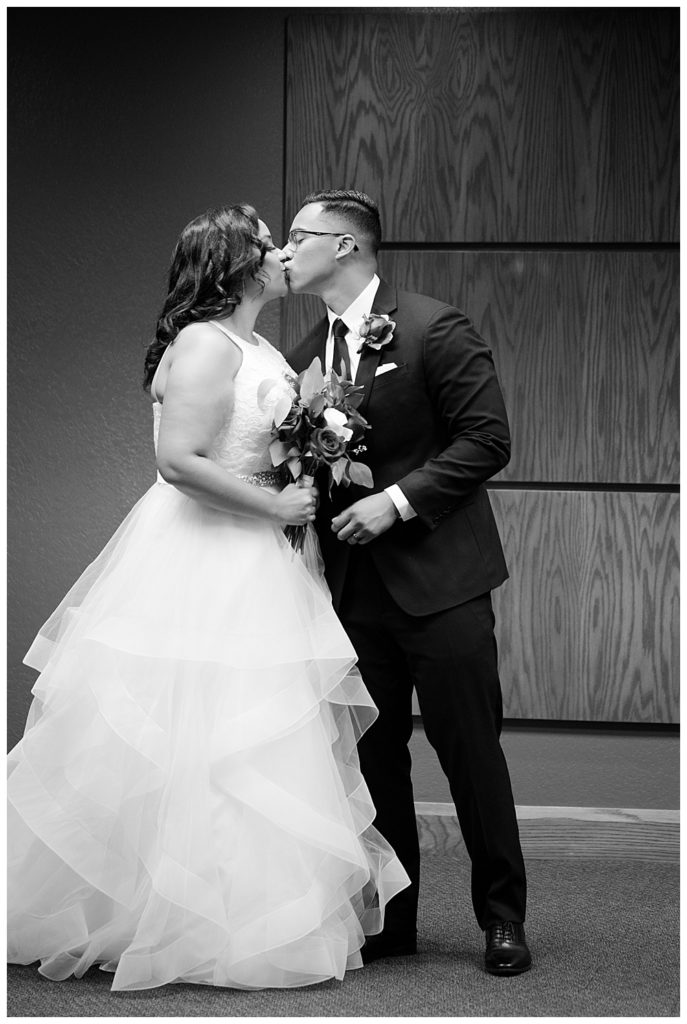black and white image of bride and groom sharing first kiss at kingdom hall