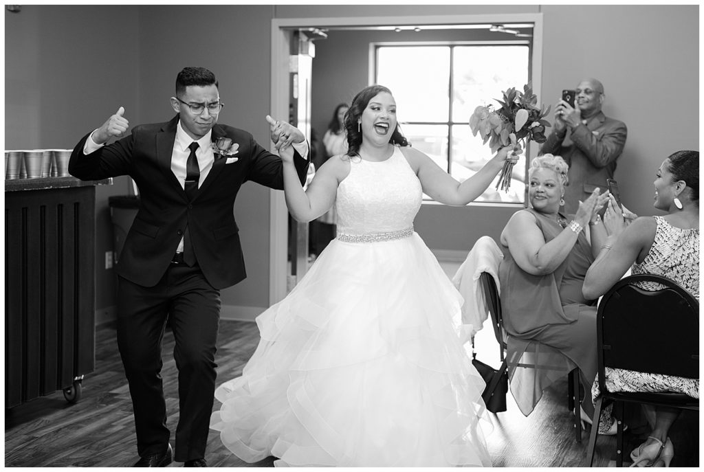 black and white image of bride and groom dancing as they enter reception at stewart hall in obetz