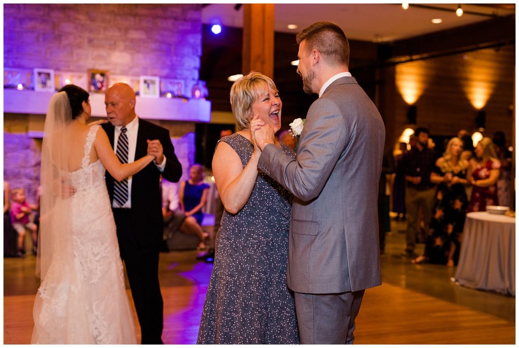 mother of groom laughing as she dances with groom at watersedge in hilliard