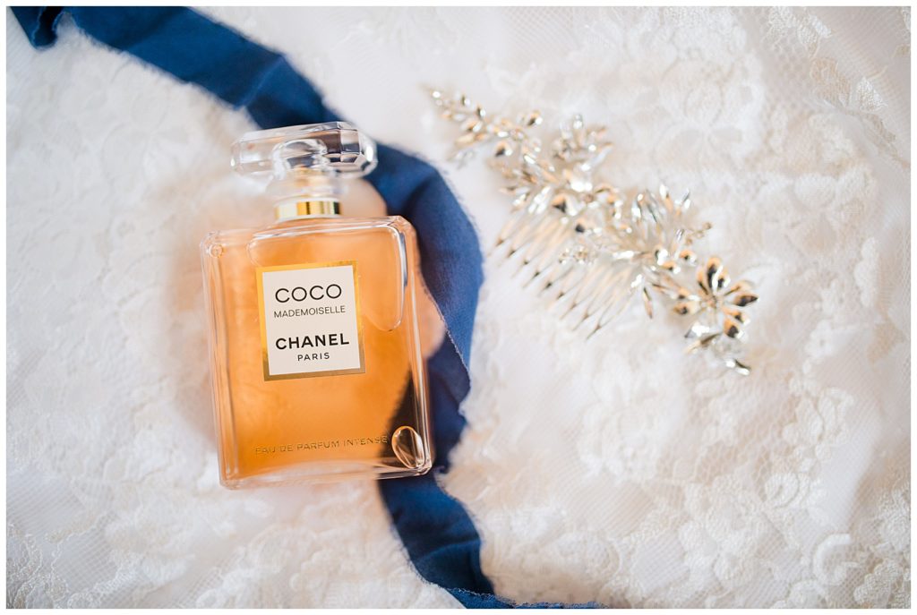 An image of a closeup view of a bride's special wedding details, showing her hair accessory, perfume, and sentimental blue item to wear by Columbus Ohio wedding photographer, Alayna Parker Photography