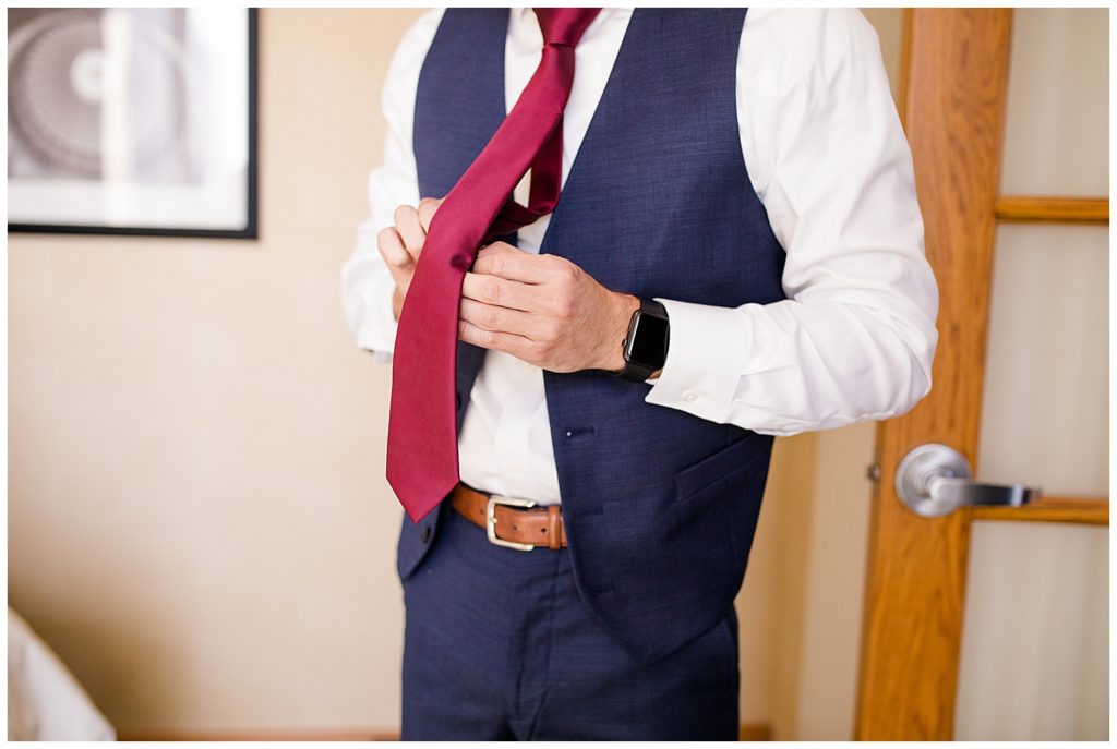 An image of a groom adjusting his tie as he prepares for his wedding ceremony by Columbus Ohio wedding photographer, Alayna Parker Photography