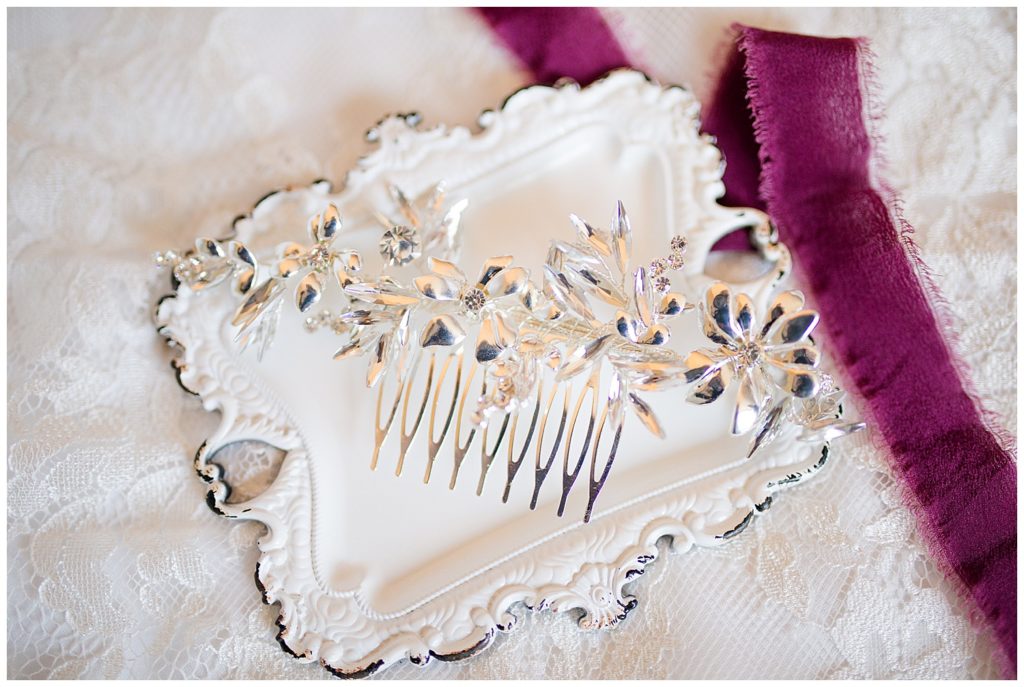 A photograph of a closeup of a bride's hair accessory resting on a background of her wedding dress by Columbus OH wedding photographer, Alayna Parker Photography