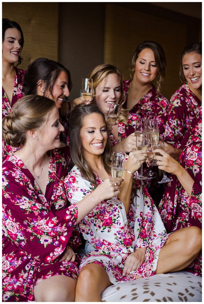 A picture of a bride and her bridesmaids relaxing and sharing some champagne before they get dressed for the wedding by Columbus wedding photographer, Alayna Parker Photography