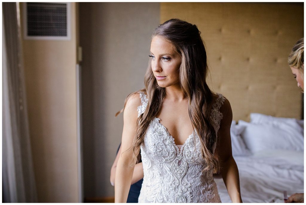 A photograph of the bride standing as her wedding dress is being adjusted shortly before the wedding ceremony by Columbus OH wedding photographer, Alayna Parker Photography