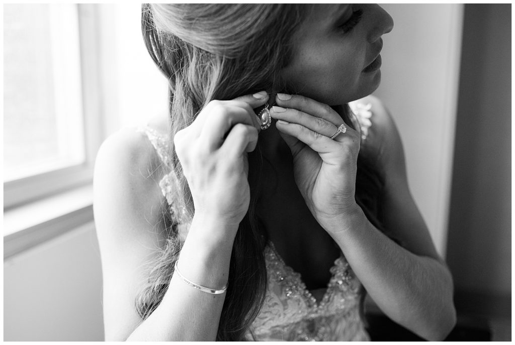 black and white image of bride putting in earring at renaissance hotel