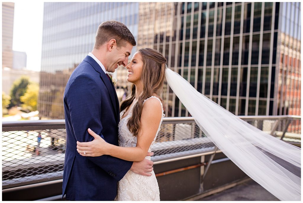 bride and groom laughing as veil blows in wind on rooftop at renaissance hotel