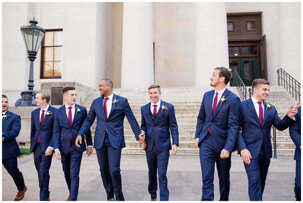 groom and groomsmen laughing and walking outside ohio statehouse