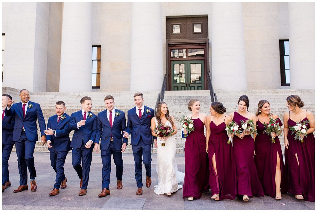 bride and groom and bridal party laughing and walking outside ohio statehouse