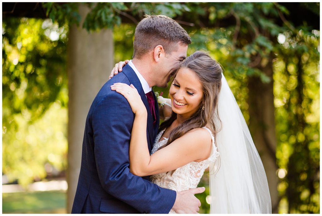 bride smiling while looking down while groom nuzzles into her at schiller park in german village