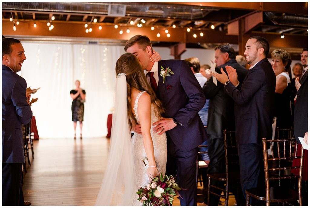 bride and groom share kiss at end of aisle at copius