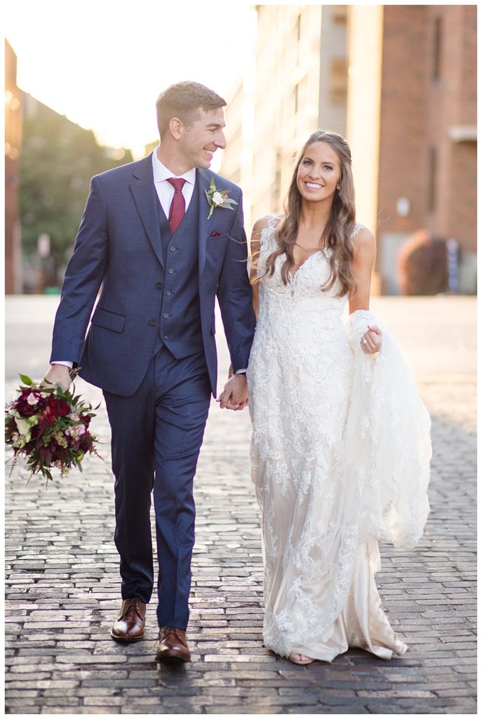 bride smiling at camera while groom smiles at bride in alley in downtown columbus