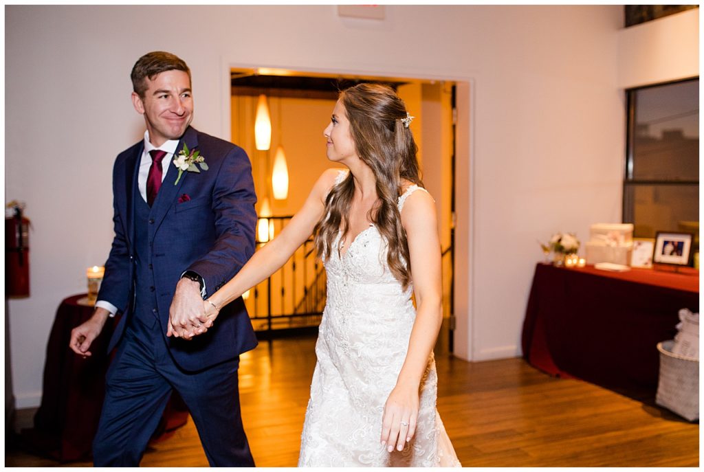bride and groom smiling at each other while they enter reception at copius