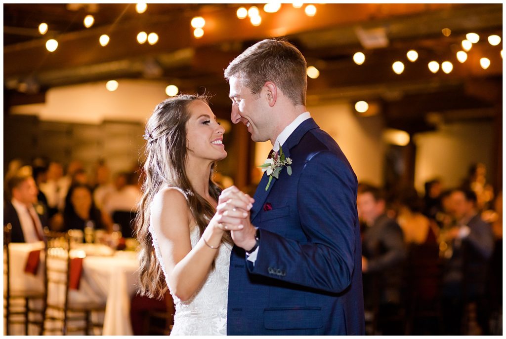 bride and groom smiling at each other while they share first dance at copius